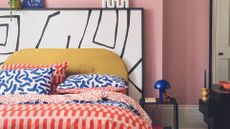 bedroom with colorful bedding, pink walls and monochrome headboard 