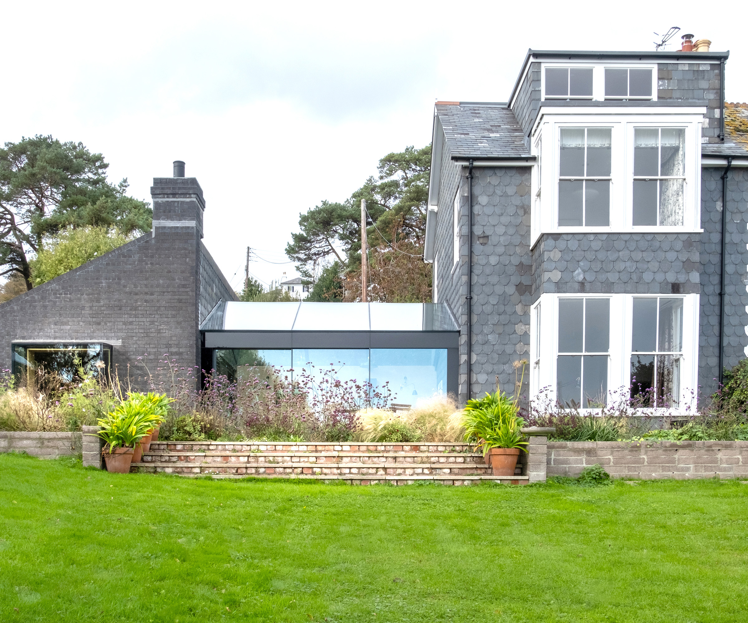 The exterior of a building with a new single storey side extension with a glass link