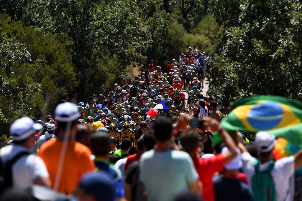 PICO VILLUERCAS SPAIN AUGUST 28 A general view of the peloton beginning to climb the Alto Collado de Ballesteros 1415m while fans cheer during the 76th Tour of Spain 2021 Stage 14 a 1657km stage from Don Benito to Pico Villuercas 1580m lavuelta LaVuelta21 on August 28 2021 in Pico Villuercas Spain Photo by Tim de WaeleGetty Images