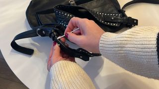 Someone using a cotton bud to clean hard to reach bits on a leather bag