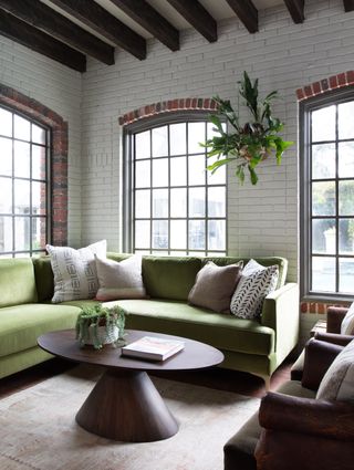 A corner living room with a green sectional, and two small armchairs