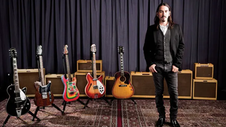 Dhani Harrison stands next to George Harrison's guitars