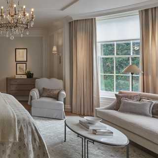 A neutrally decorated bedroom with a sofa in the bay window