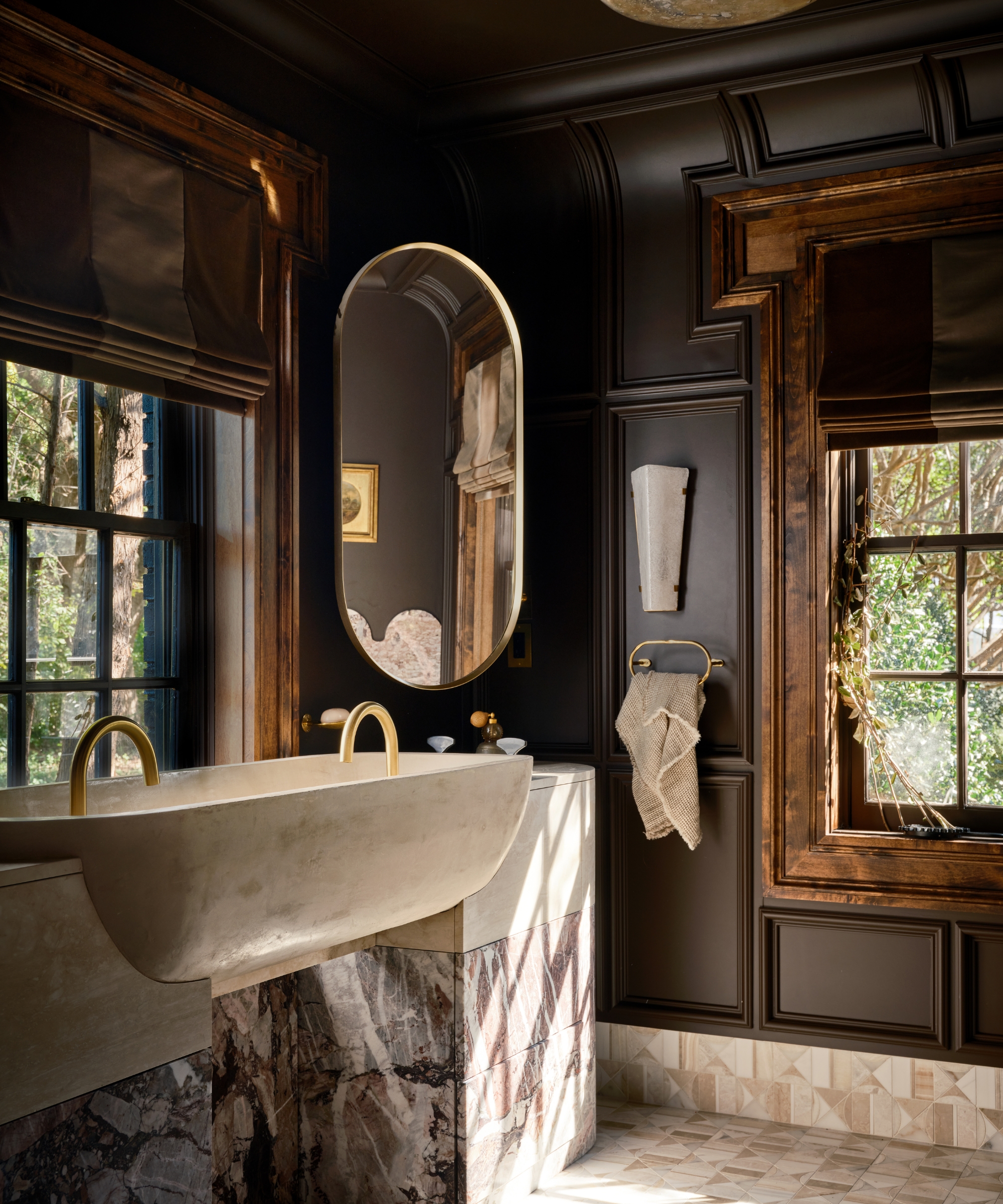 A large bathroom with dark brown walls and ceiling and marble accents throughout
