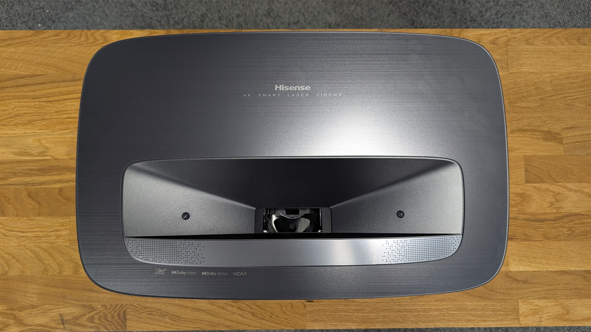 Hisense PL2 UST projector on wooden hi-fi rack top down view showing lens aperture