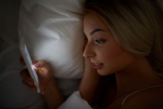 A woman in bed looking at her smartphone.