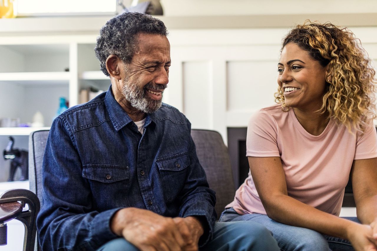 A woman smiles while sitting next to her father. 