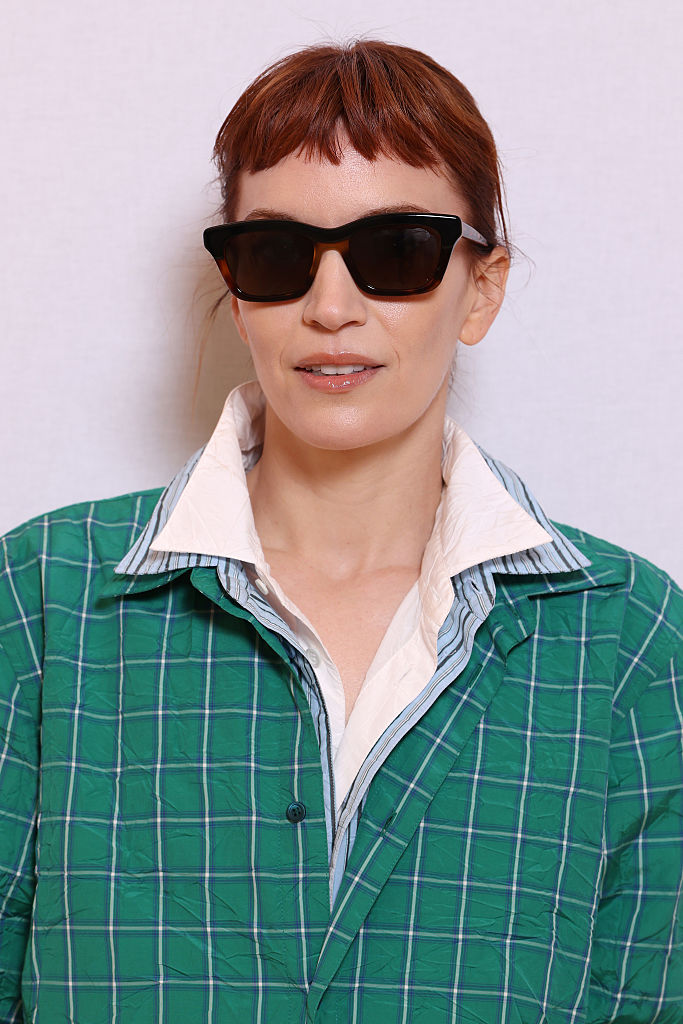 Britt Lower at Loewe with baby bangs and red hair in a green button down