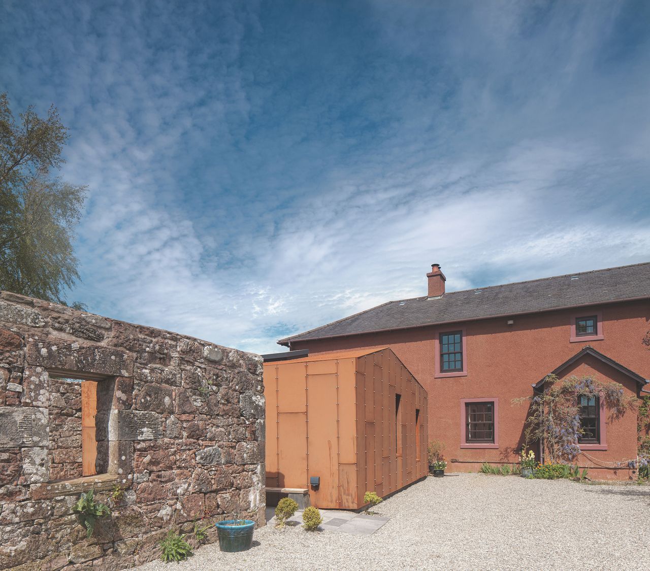 red and stone extension to red farmhouse exterior