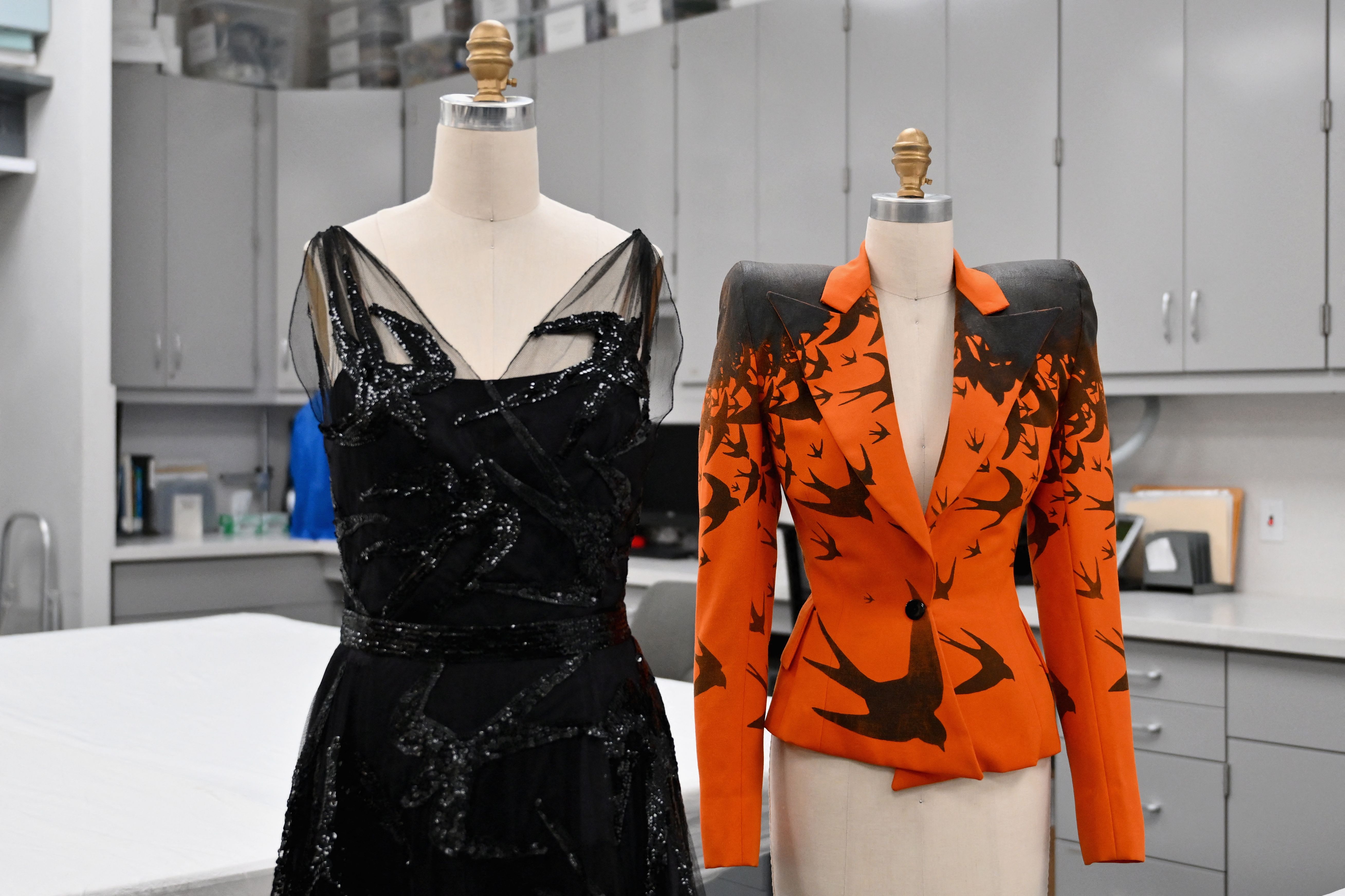 two mannequins, one with a black dress and one with an orange blazer