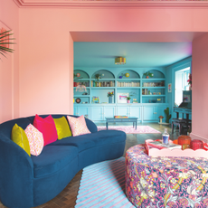 Pink drenched living room wich leads to dining room drenched in blue paint