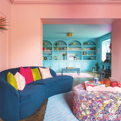 Pink drenched living room wich leads to dining room drenched in blue paint