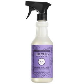 A clear bottle of Mrs. Meyers multi-surface spray with a purple label and black spray lid