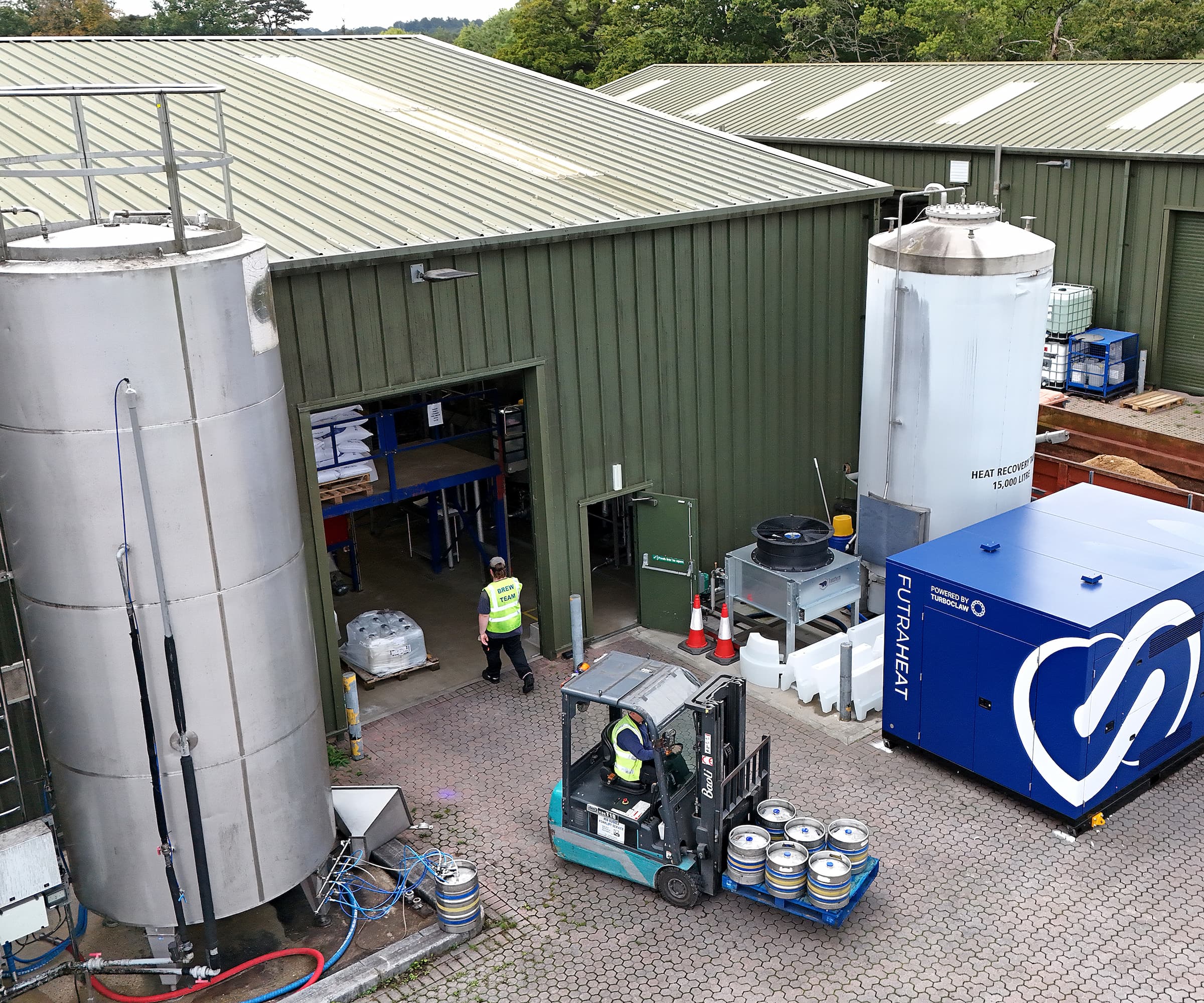 A brewery with corrugated sheet walls and roof with a large blue heat pump outside