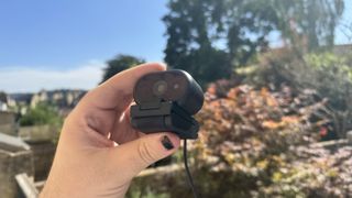Dell Pro 5 webcam on its stand, in a hand, outside