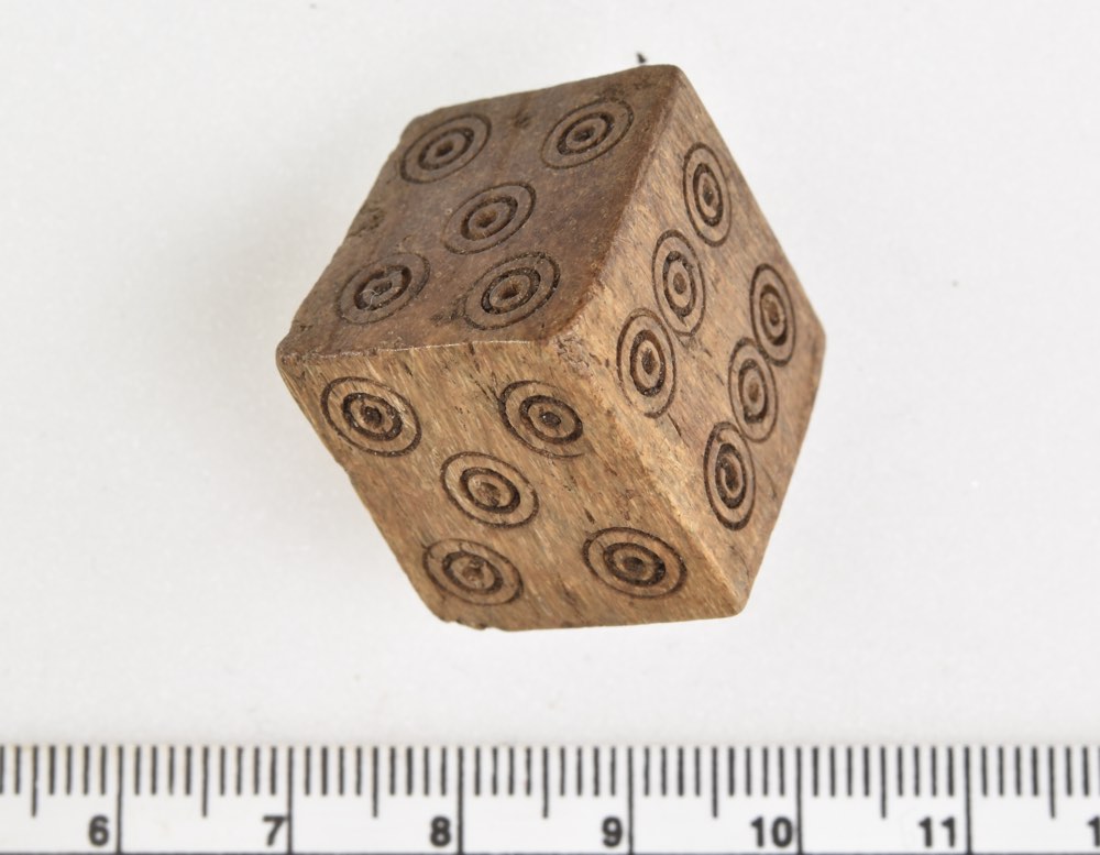 The wooden dice has two 4s and two 5's but no 1 or 2. Archaeologists believe that it was likely used to cheat while gambling. This photo shows the two 4's.