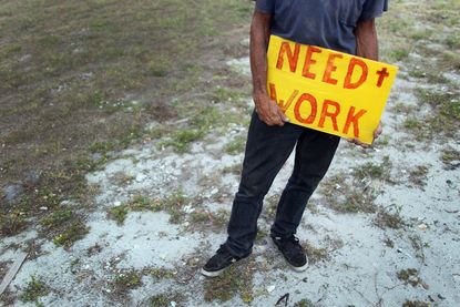 An unemployed man works a street corner hoping for a job.