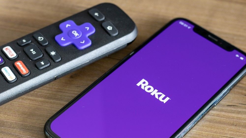 Roku remote next to iPhone with Roku logo on its screen