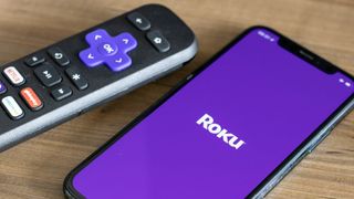 Roku remote next to iPhone with Roku logo on its screen