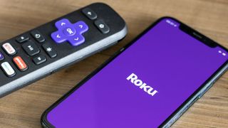 ROKU מרוחק ליד ה- iPhone עם לוגו של Roku על המסך שלו