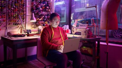 A person sitting in a shop working on a MacBook Neo