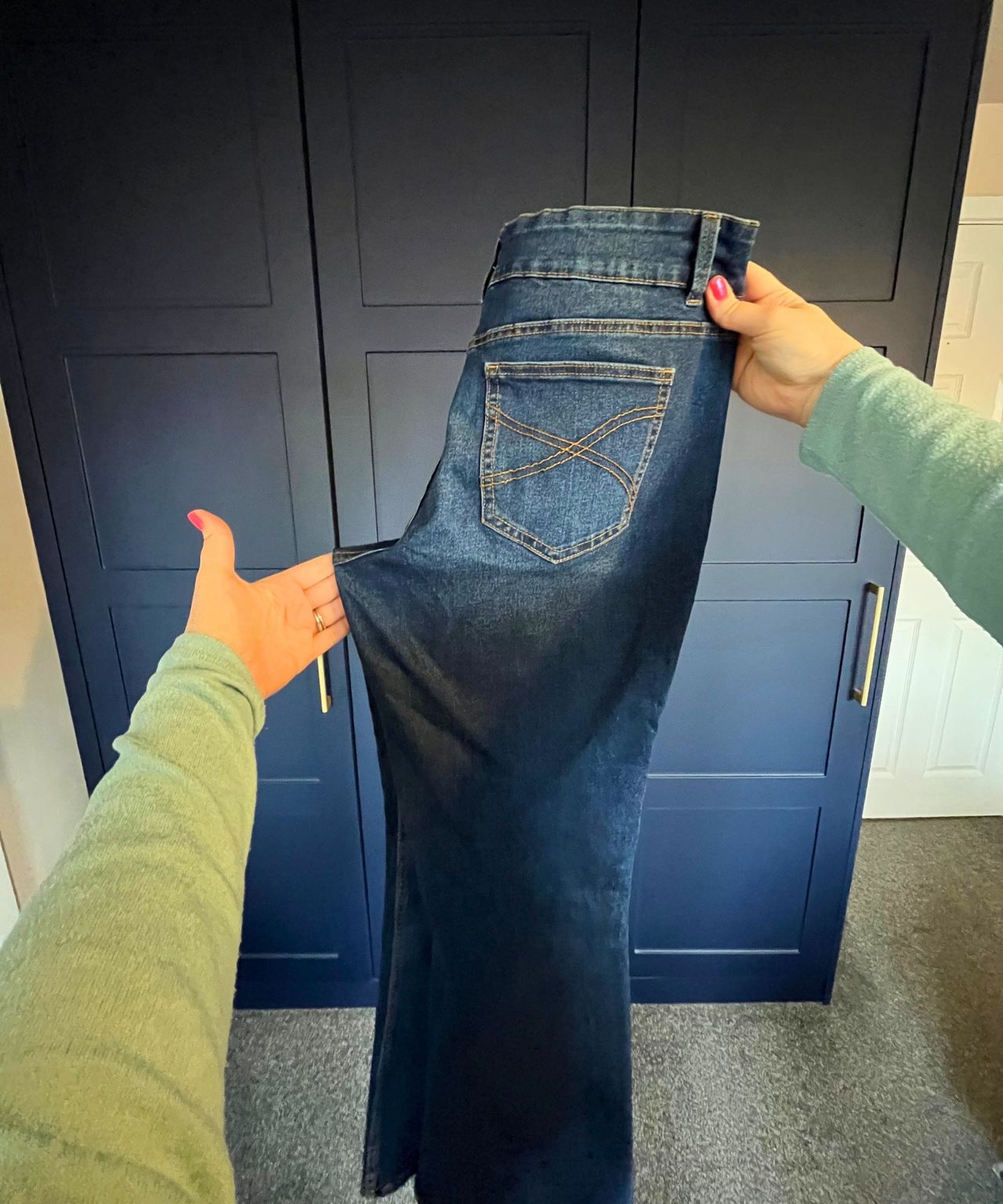 Pictured is the pair of jeans now folded vertically so the zip falls inside and you can now see the in-seam on the left side that is being pulled out to a point and neatened up