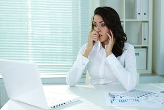 A woman looks with worry at a computer.