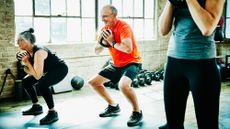 Older workout class squat while carrying a kettlebell