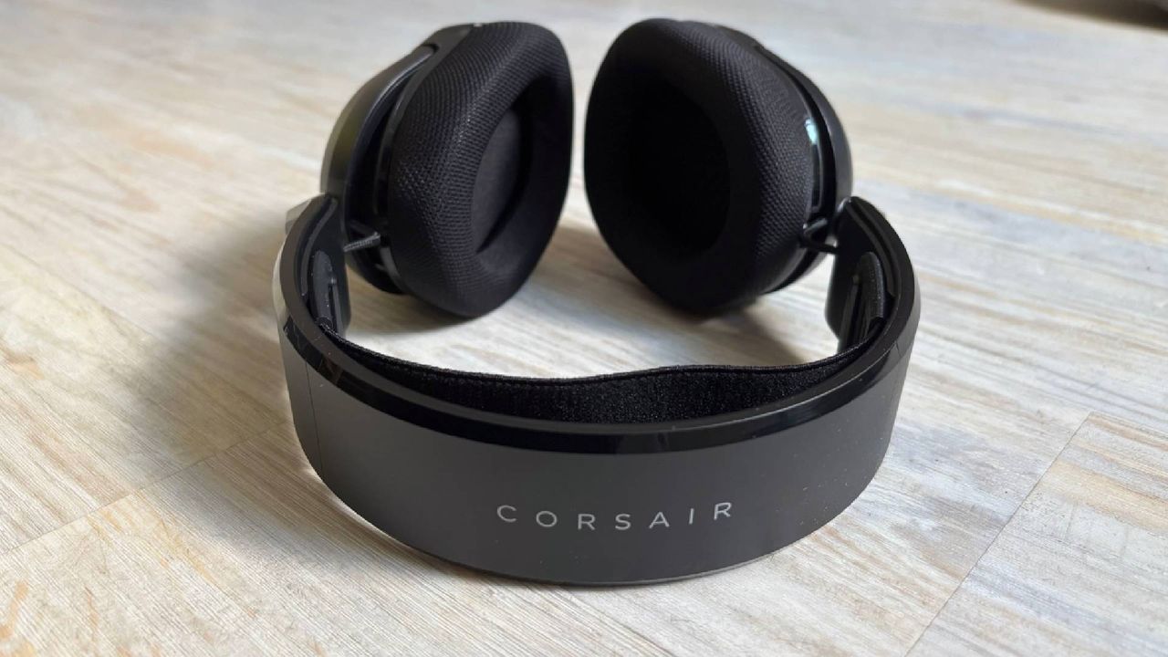 Corsair HS35 v3 headband showing corsair branding in white, with earcups in background against a white hardwood floor
