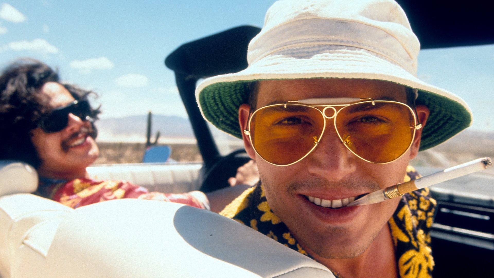 An image from Fear and Loathing in Las Vegas of two people sat in a car whilst looking at the camera. 