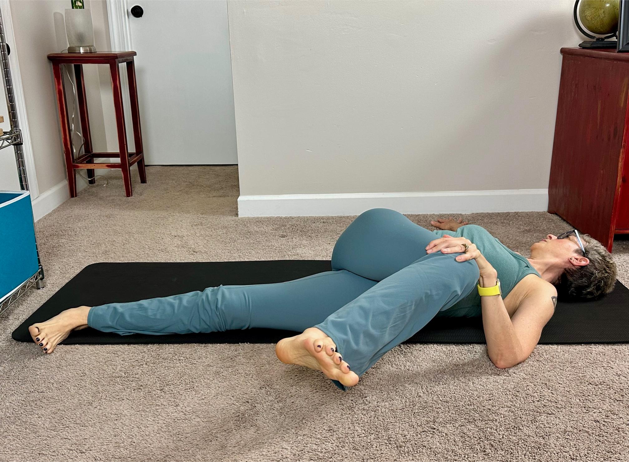 woman lying on her back performing a spinal twist with one knee crossed over her body