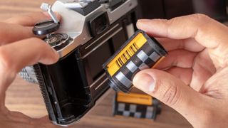 A hand loading film into a film camera