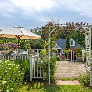 Garden terrace with sun umbrella. New England Style renovation. A renovated and extended1920s country house in the New England style, in Surrey, England, home of JP Clark and husband