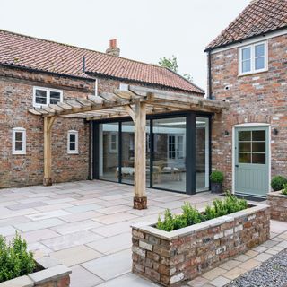 Brick farmhouse with modern extension and wooden pergola