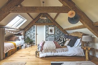 A loft conversion bedroom with two beds and exposed timber beams