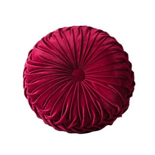 A circular pleated burgundy pillow with a tufted-button middle