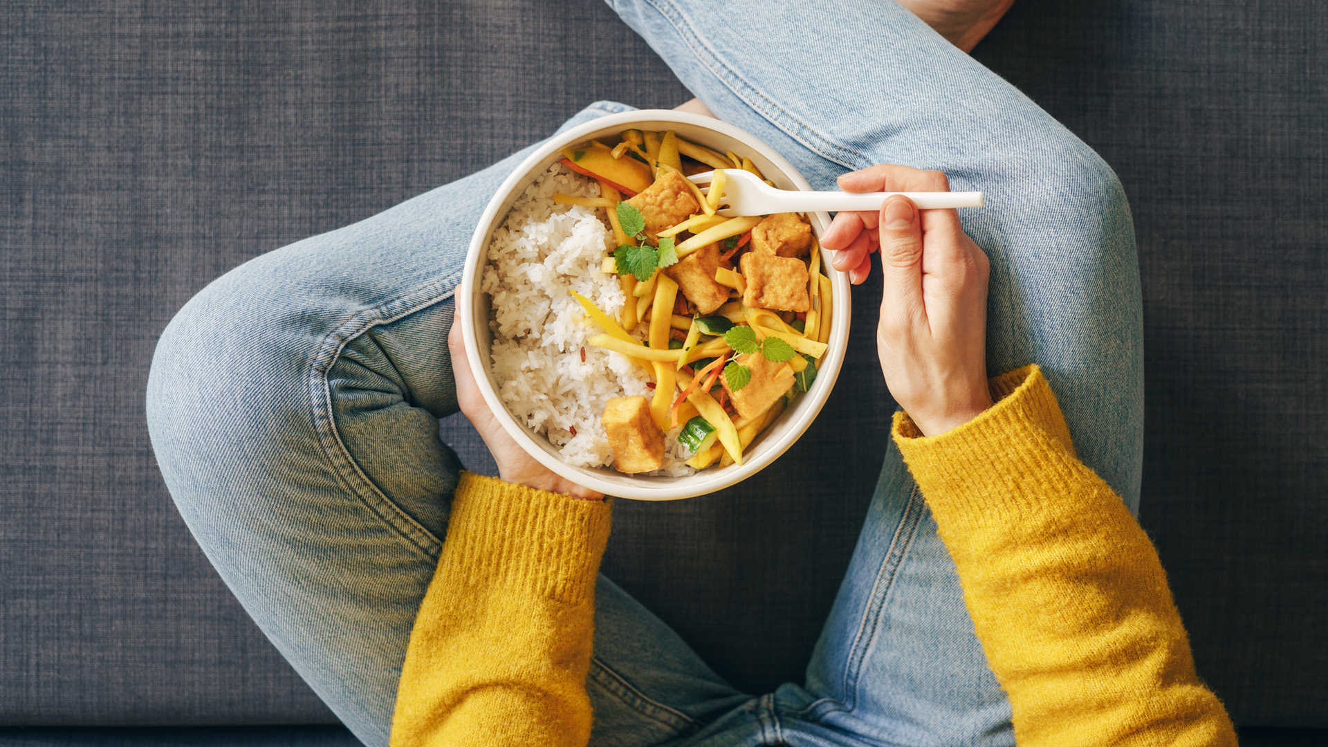 mujer comiendo un plato de arroz blanco con tofu