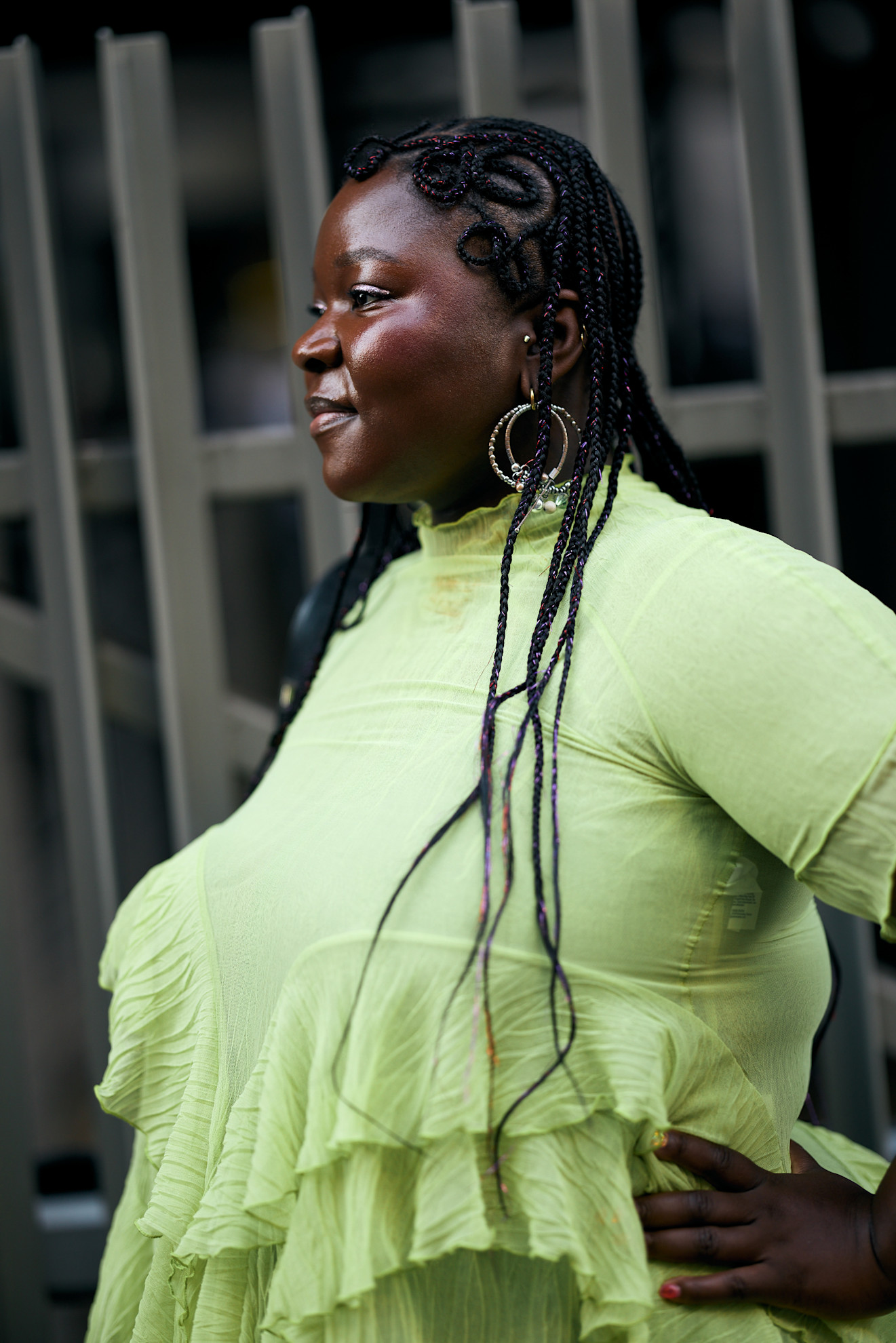 a black woman in a green dress with a braided hairstyle and silver hoops