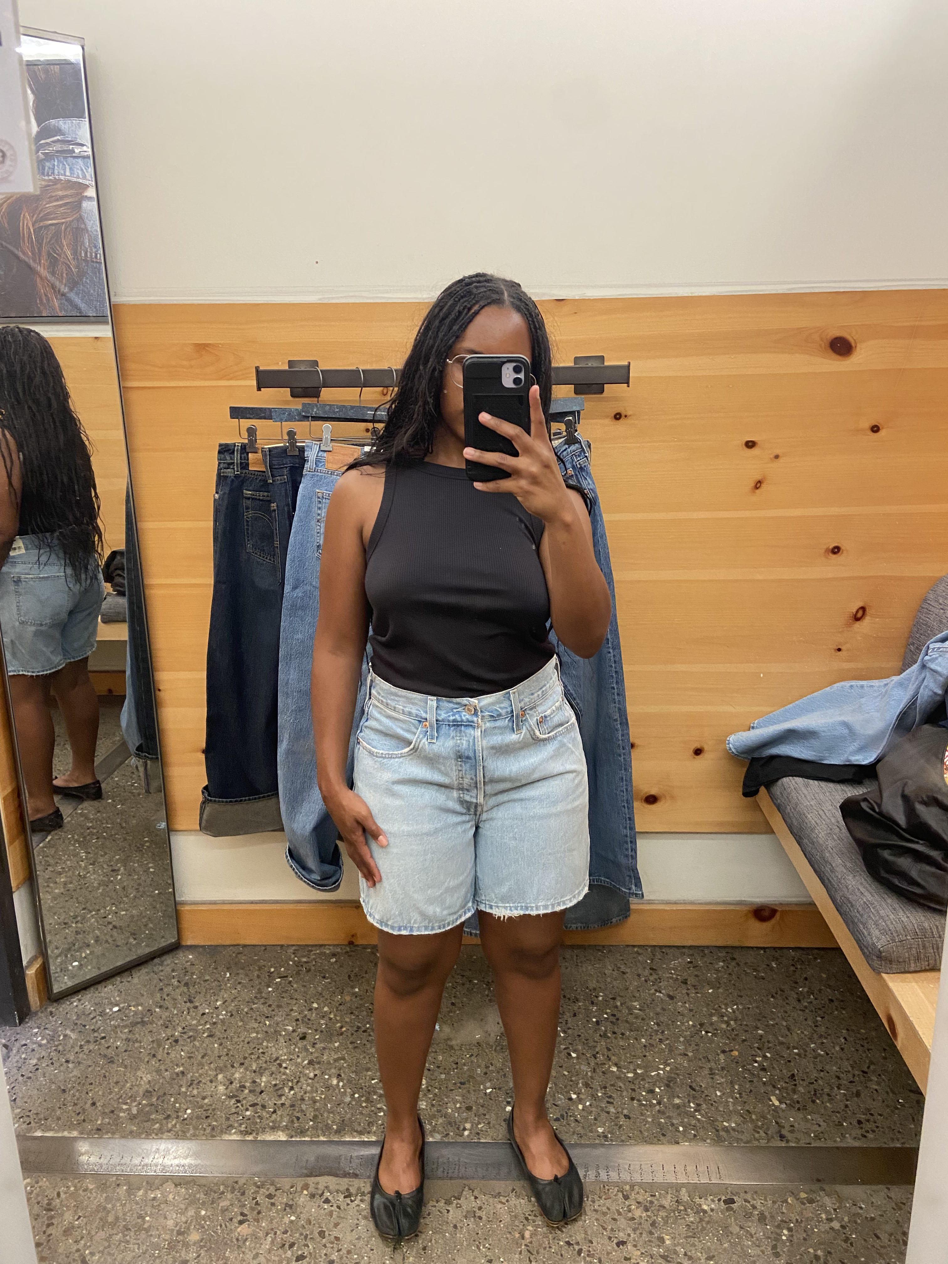 a woman wearing a black tank top and blue denim shorts