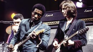 American guitarist Buddy Guy (left) performs live on stage with English guitarist Eric Clapton at the Supershow session at a disused factory in Staines, England on 26th March 1969. Eric Clapton plays a 1964 Gibson Firebird guitar. 