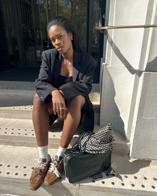 @nlmarilyn wears brown suede trainers with black tailored shorts