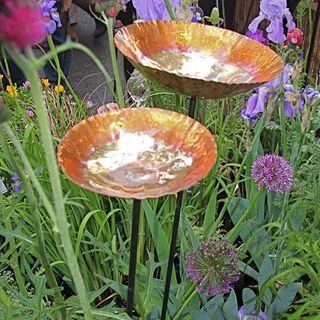 copper bird bath with flower plants