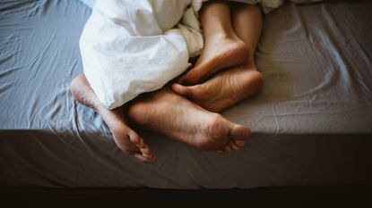 Feet of a couple in bed - stock photo for sex therapy app Lover