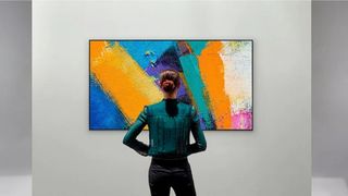 LG GX Series mounted to wall in art mode with woman viewed from behind