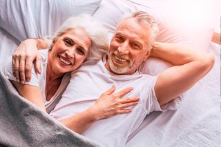 Older woman and man cuddling in bed