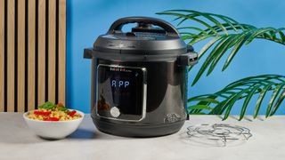 a black smart home enabled wi-Fi instant pot with a touchscreen and a 6QT inner pot is photographed against a blue background