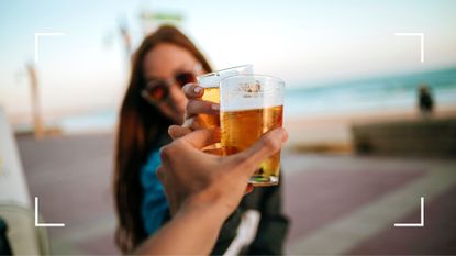 Two women clinking glasses of low-calorie beer on the beach
