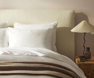 Corner of Brooklinen Luxury Sheet Set on a bed against a cream wall.