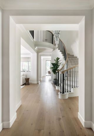 curved staircase and spacious entrance hallway with pale wooden floors and crystal lightfitting