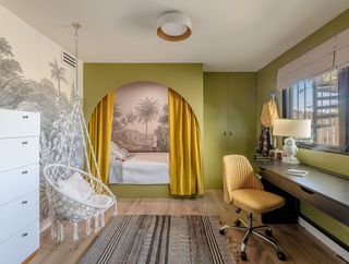 A bedroom with a curtain surrounding the bed, a whimsical wallpaper, and a hanging macrame chair